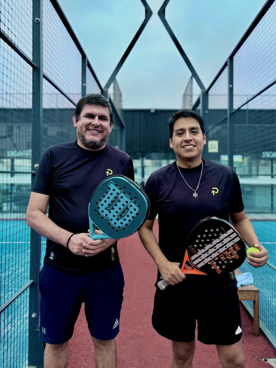 Dos jugadores de la comunidad Padelhood sonriendo con sus raquetas en la cancha